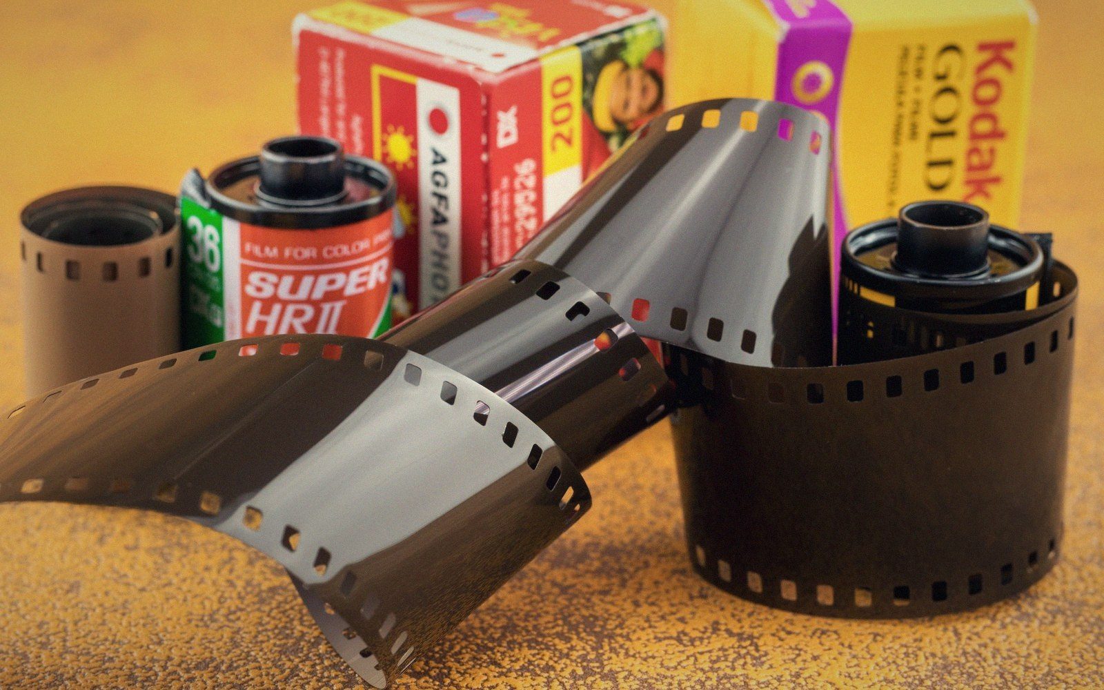 Coiled 35mm film canisters and strips beside Agfa and Kodak film boxes