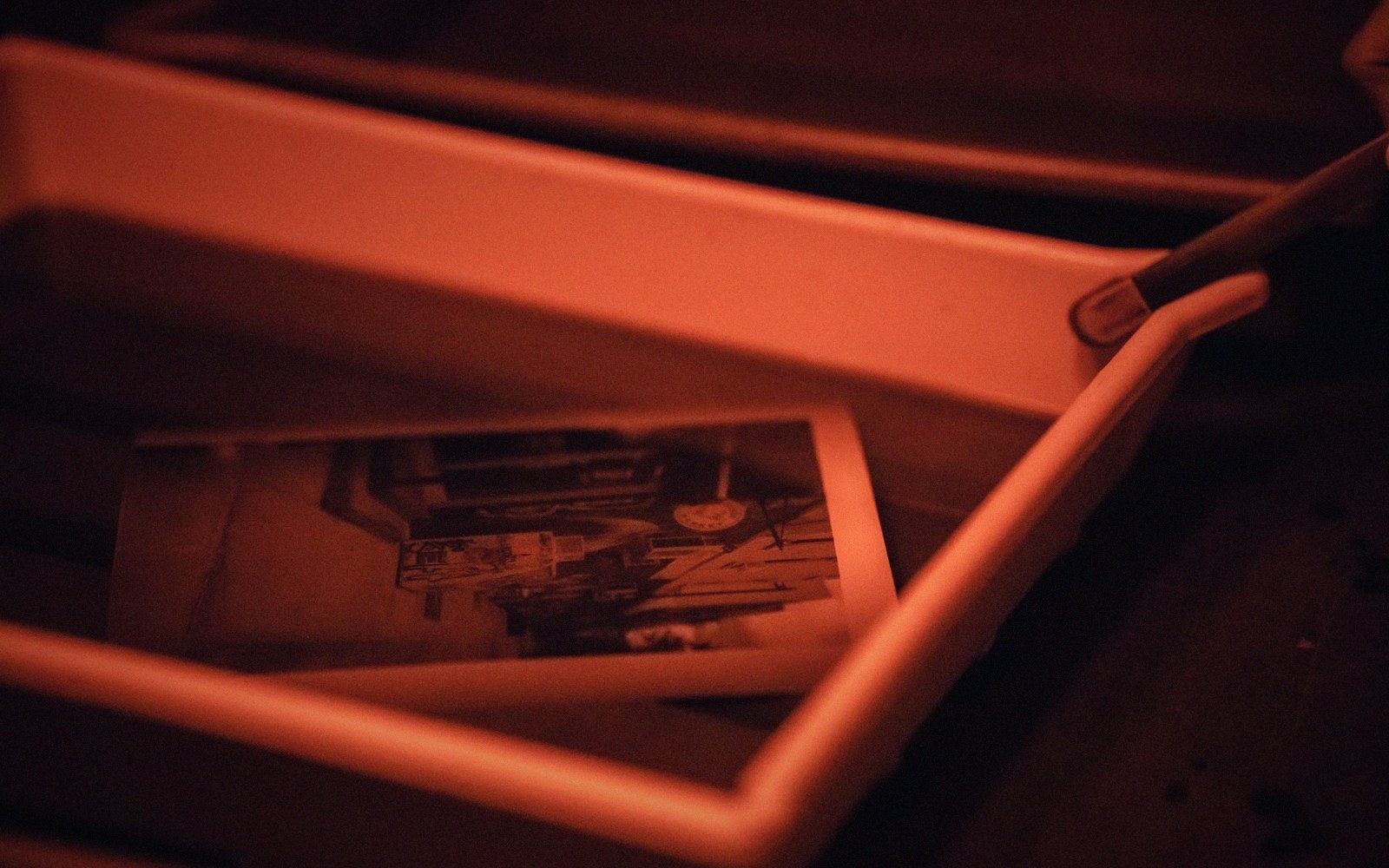 A plate being coated in a darkroom under safelight